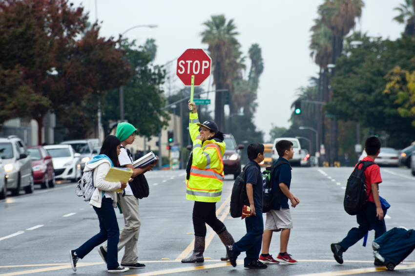 Crossing guard holding up a stop sign helping kids cross the street