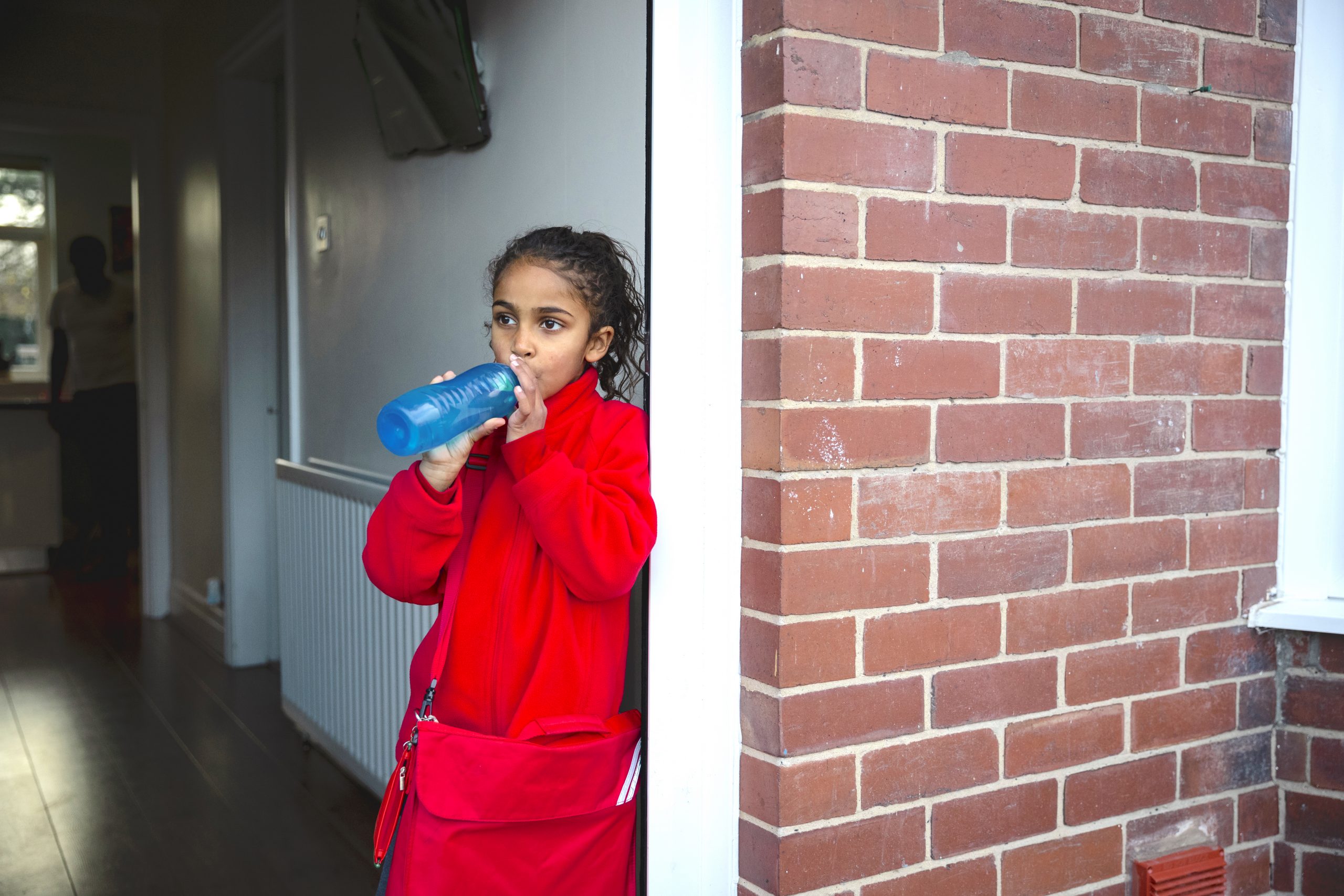 School-aged girl drinking water from a reusable water bottle