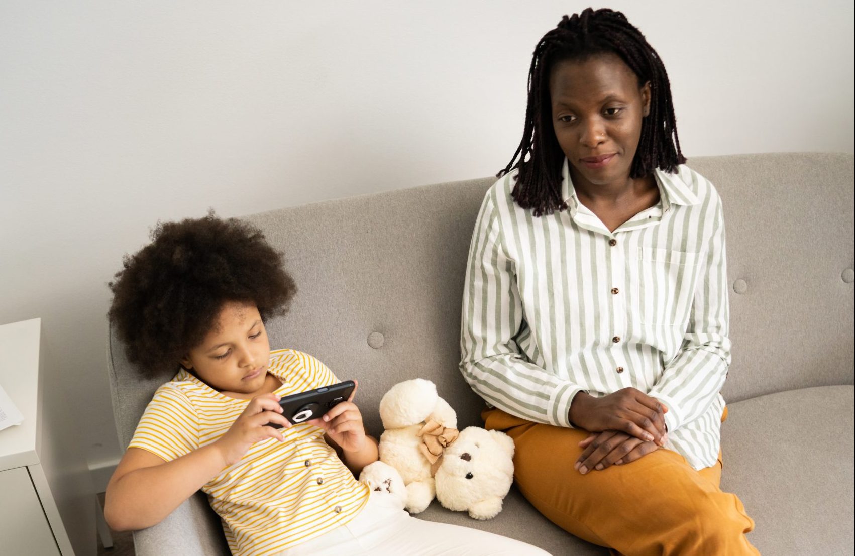 Mom and daughter meeting with counselor at home, while daughter is looking at a handheld screen